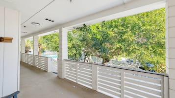 Un pasaje cubierto con barandillas blancas y vistas a una piscina y árboles.