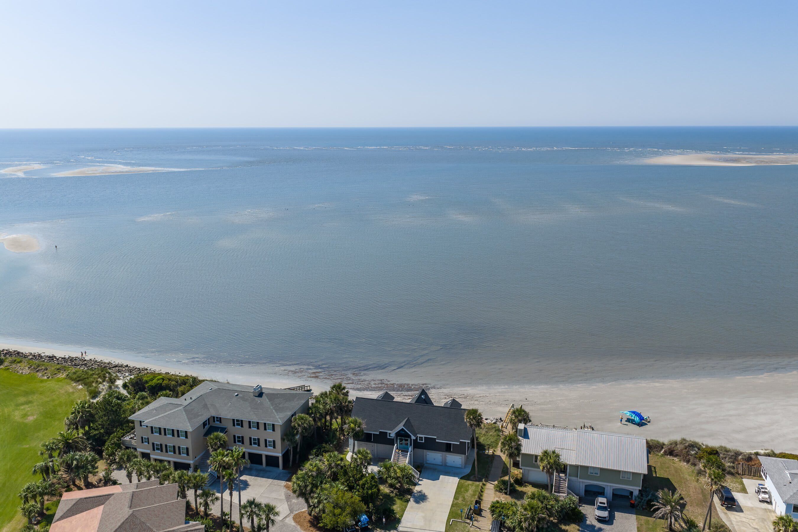 A coastal property with a large house, a beach, and a clear view of the ocean.