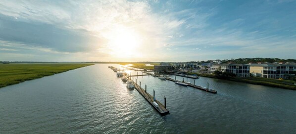 A riverfront marina with boats docked, a pier, and buildings along the riverbank.