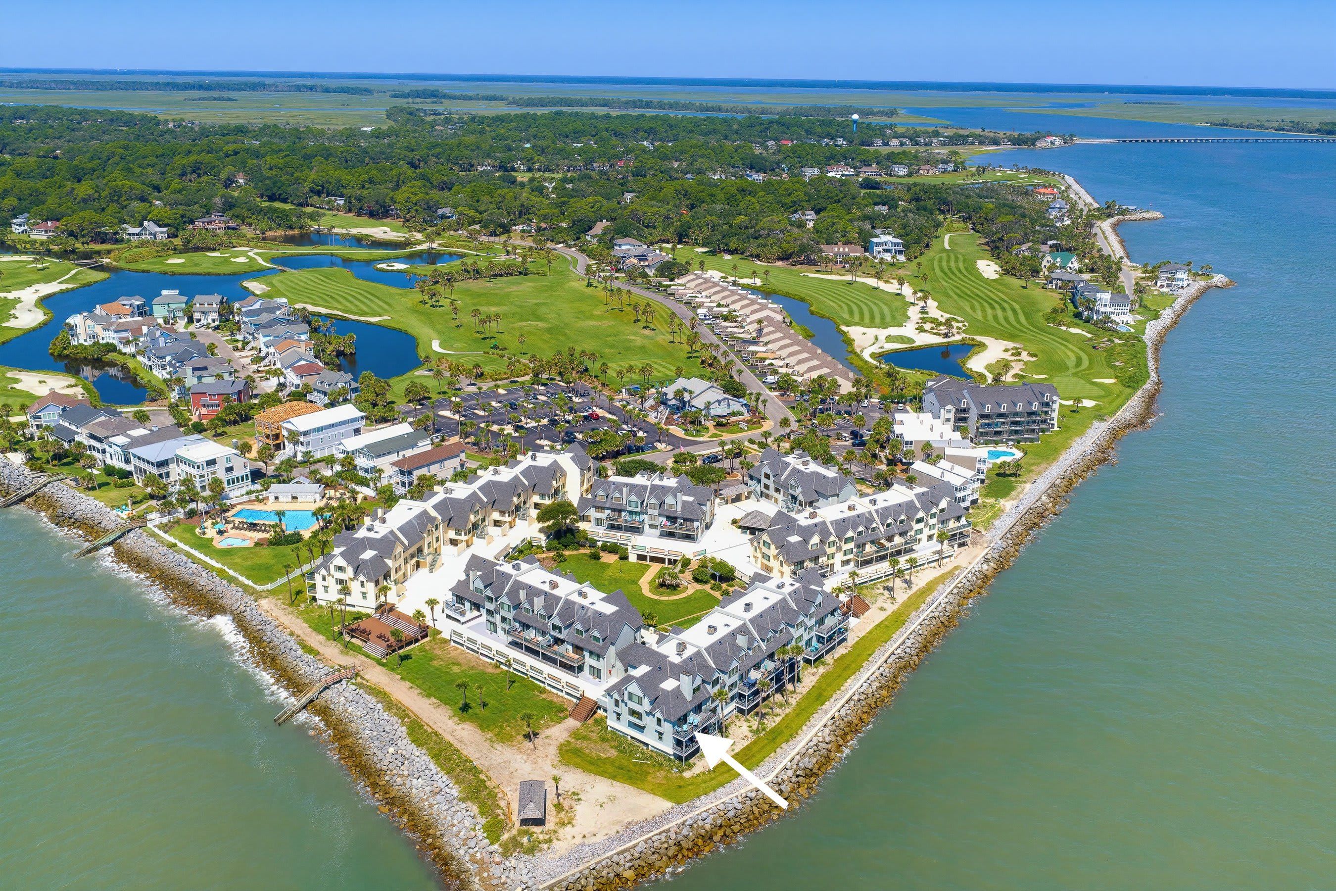 Un complex turístic costaner amb diversos edificis, un camp de golf i una marina.