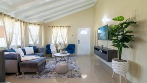 Una sala de estar con un sofá modular, una mesa de centro redonda y una planta grande.