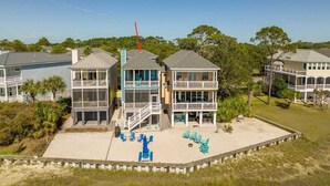 Une propriété située en bord de mer, comprenant plusieurs bâtiments, un patio couvert avec des chaises et une vue sur l’océan.