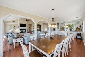 A spacious living area with a dining table, sofas, and a kitchen in the background.