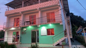 A two-story building with a green facade, a covered balcony, and a staircase leading to the upper floor. - Casa Guiwa Hostel (Dibulla)