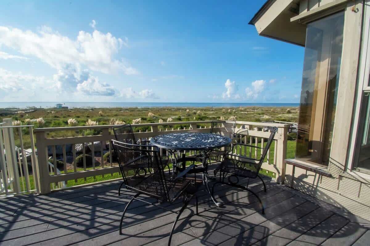 Un balcon avec une table et des chaises donnant sur un paysage côtier.