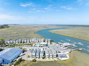 Un hotel sulla costa con edifici a più piani, una marina con barche e un fiume sullo sfondo.