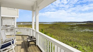 A covered porch with white railings, a bench, and a table. - 867 Bonito Road (Fripp Island)
