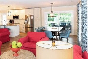 Una cocina moderna con electrodomésticos de acero inoxidable, una zona de comedor con sillas azules y un sofá rojo.
