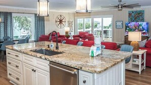 A spacious kitchen with a granite island, white cabinetry, and a large window.