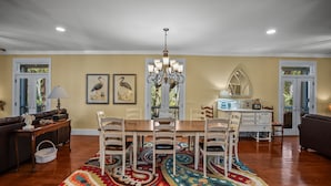 A dining area with a chandelier, wooden chairs, a table, and a patterned rug.