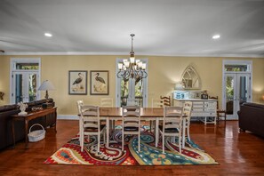 A dining area with a chandelier, wooden chairs, a table, and a patterned rug.