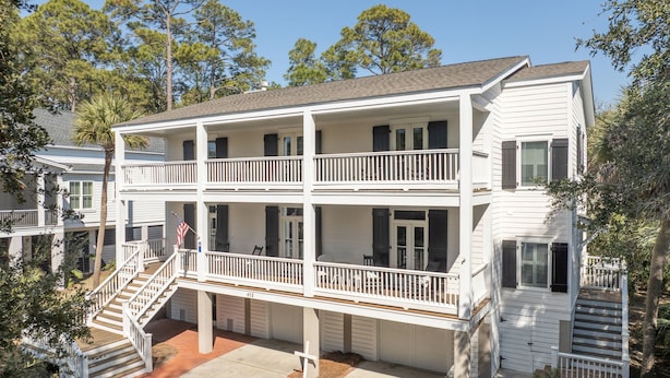 A two-story building with a balcony on the second floor, a front staircase, and a flag.