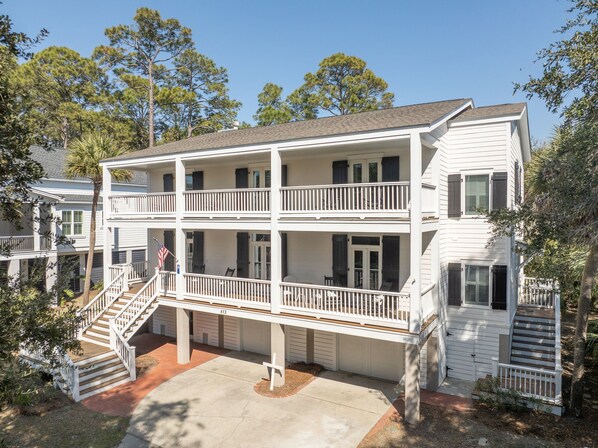 A two-story building with a balcony on the second floor, a front staircase, and a flag.
