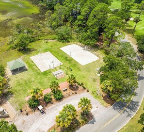 An aerial view of a property with a basketball court, a small pavilion, and a parking area.