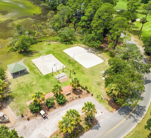 An aerial view of a property with a basketball court, a small pavilion, and a parking area.