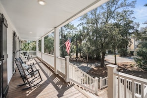 A covered porch with a view of a residential street and trees.
