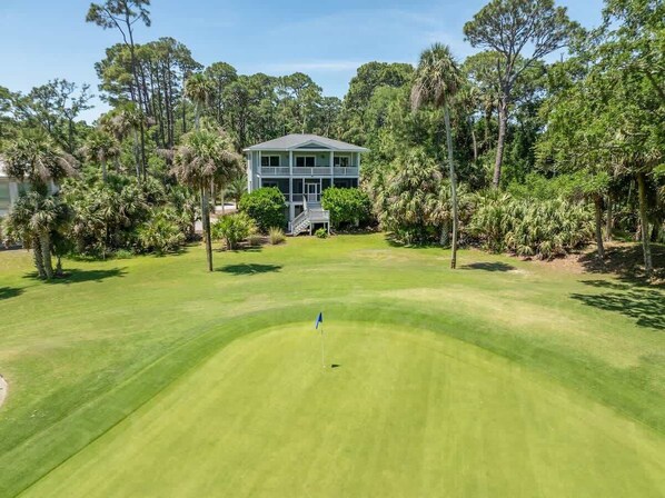 Um campo de golfe com uma casa ao fundo.