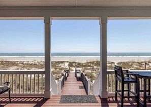 En overdækket terrasse med udsigt til stranden, et bord og stole.