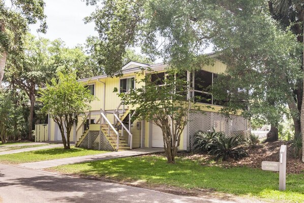 A yellow building with a staircase, a fenced area, and a sign reading 'DOLPHIN ROAD.'
