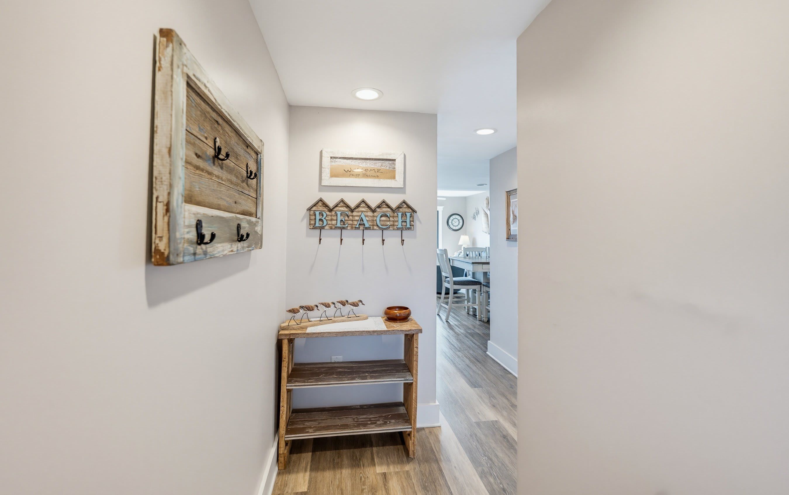 A hallway with a rustic wooden wall decor, a wall-mounted birdcage, and a small wooden shelf with decorative items.