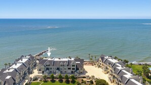 Un hôtel situé sur la côte, composé de plusieurs bâtiments à étages, avec une plage et un rivage rocheux.