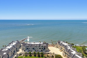 Un hôtel situé sur la côte, composé de plusieurs bâtiments à étages, avec une plage et un rivage rocheux.
