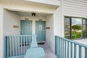 A building with two doors, each marked with a number. There is a small porch area with a light fixture above and a window to the right.