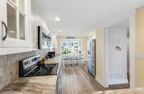 A modern kitchen with a central island, built-in appliances, and a view to the dining area.