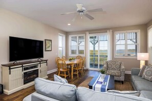 A living room with a flat-screen TV, a dining table with chairs, a ceiling fan, and a sofa. - 15 Quarterdeck Lane (Fripp Island)
