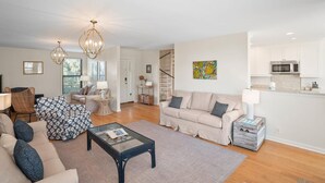 A living room with a sofa, armchairs, a coffee table, and a staircase leading to a kitchen. - 112 Capt John Fripp Villa (Fripp Island)