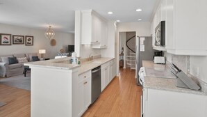 A modern kitchen with white cabinetry, a central island, and a built-in dishwasher. - 112 Capt John Fripp Villa (Fripp Island)