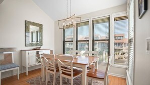 A dining area with a wooden table and chairs, a chandelier, a cabinet, and a window with blinds. - 112 Capt John Fripp Villa (Fripp Island)