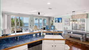 A kitchen with a blue countertop, white cabinets, a dishwasher, and a view of the ocean. - 12 Sea Mist Road (Fripp Island)