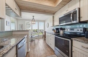 A modern kitchen with granite countertops, stainless steel appliances, and a view to the outdoors. - The Lone Palm - Resort Access Included! (Fripp Island)