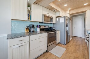 Une cuisine moderne avec des meubles blancs, un réfrigérateur en acier inoxydable, un four à micro-ondes et une cuisinière.