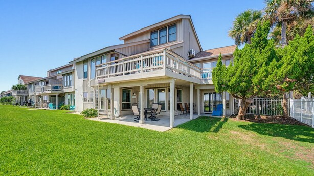 A two-story house with a covered patio and a fenced yard.