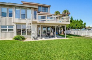 A two-story house with a balcony, a covered patio, and a well-maintained lawn. - 143 Captain John Fripp Villa - The Lone Palm (Fripp Island)