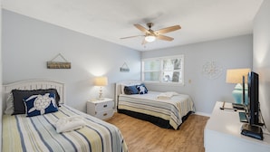 A bedroom with two beds, a ceiling fan, a window with blinds, and a desk with a computer. - 143 Captain John Fripp Villa - The Lone Palm (Fripp Island)