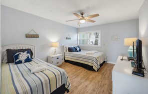 A bedroom with two beds, a ceiling fan, a window with blinds, and a desk with a computer. - 143 Captain John Fripp Villa - The Lone Palm (Fripp Island)