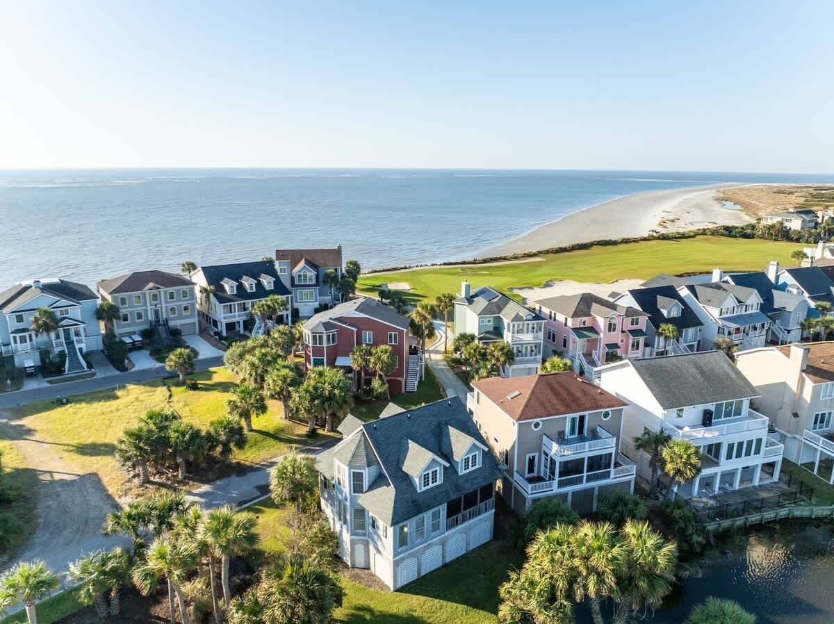 A coastal residential area with houses, a beach, and a clear view of the ocean.