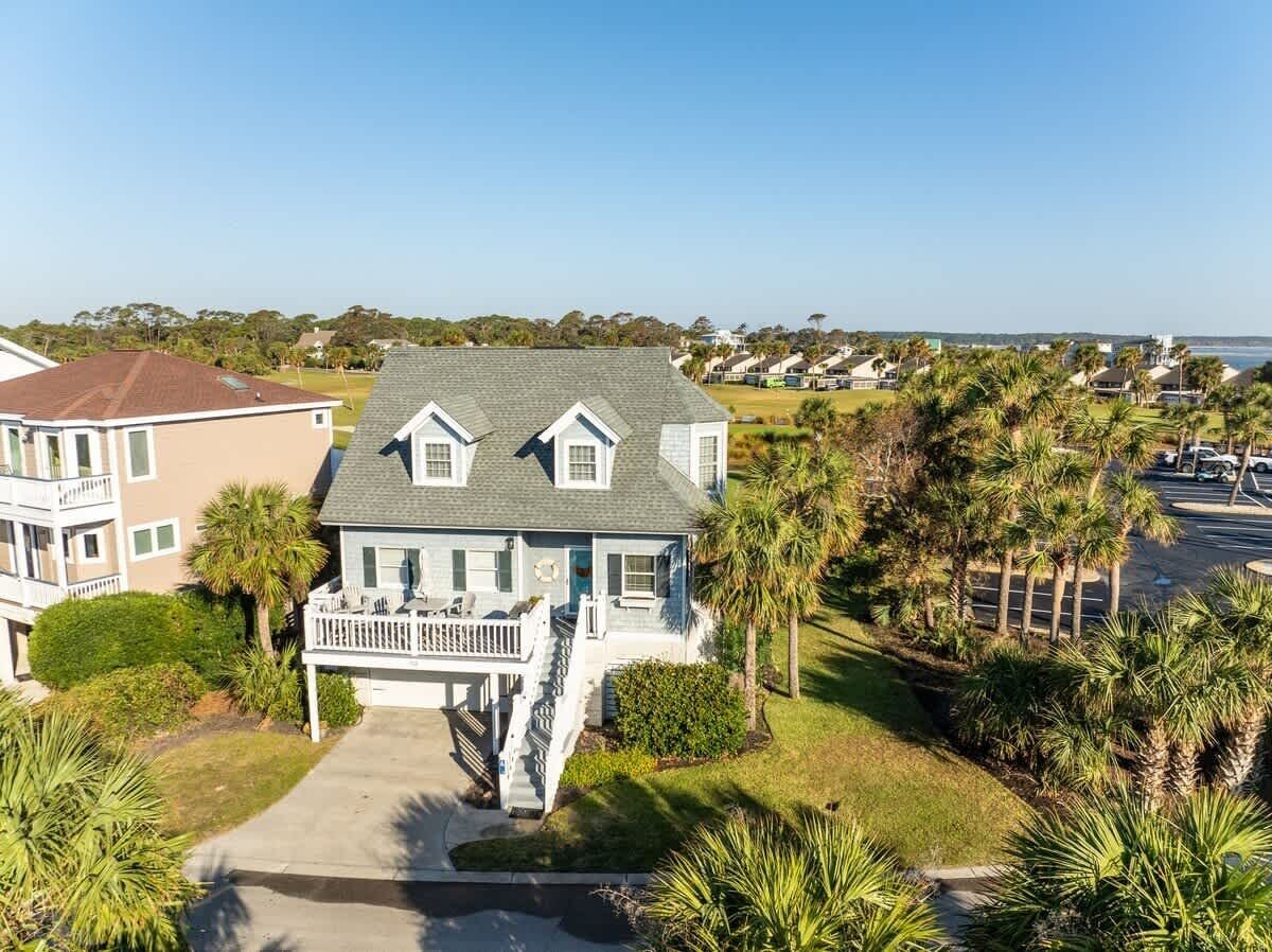 A two-story house with a front porch, a driveway, and a view of the ocean.