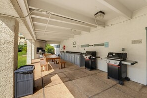 An outdoor patio with a barbecue grill, a table, and a trash bin. - 665 Newhaven (Fripp Island)