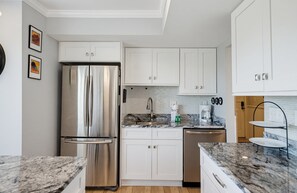 Eine moderne Küche mit weißen Schränken, Edelstahlgeräten und Granit Arbeitsplatten.