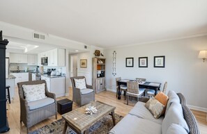 A modern living room with a sofa, two armchairs, a coffee table, and a dining area with a table and chairs. - 665 Newhaven (Fripp Island)