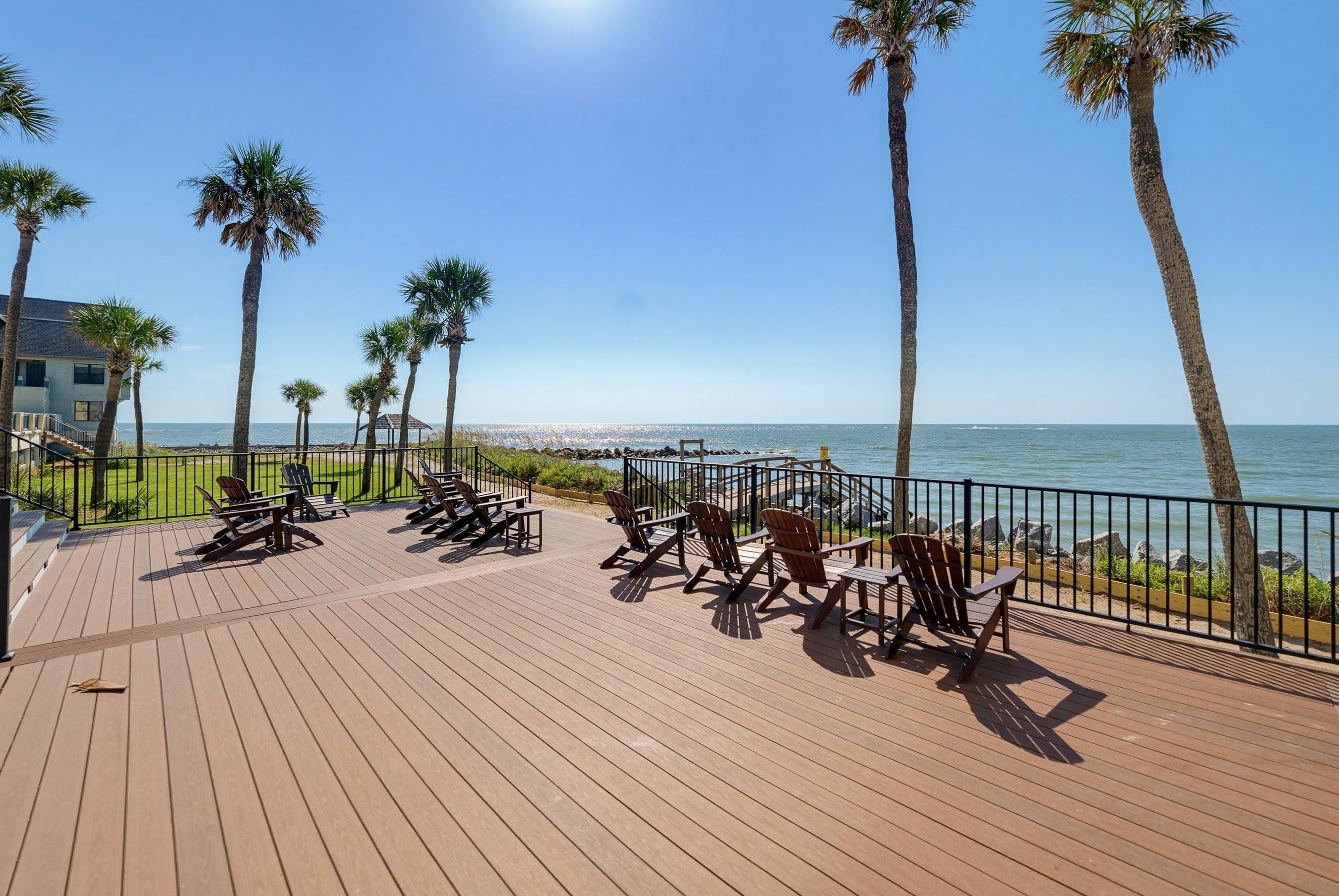 A wooden deck with outdoor seating and a view of the ocean.