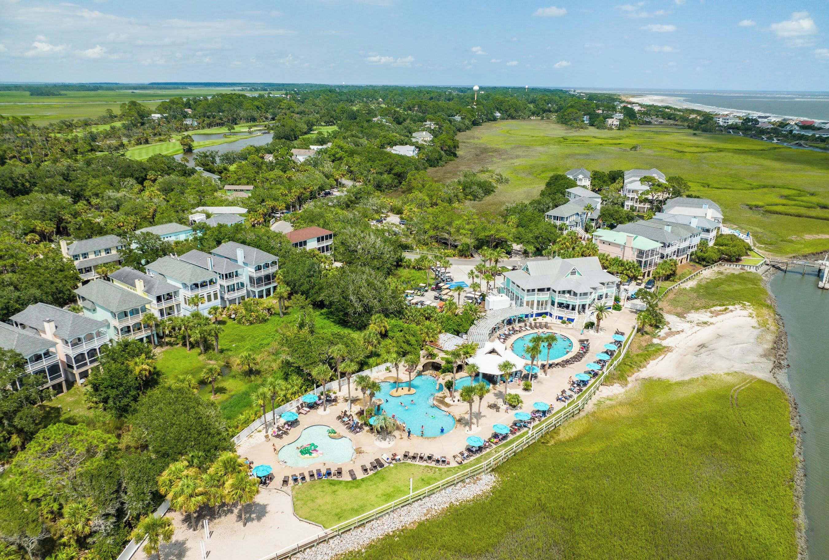A resort with multiple buildings, a large swimming pool area, and a view of the surrounding landscape.