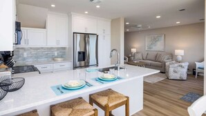 Une cuisine moderne avec des meubles blancs, un réfrigérateur en acier inoxydable et un îlot central doté de tabourets.