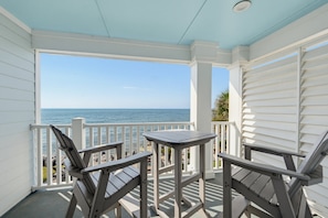 A covered outdoor seating area with a table and chairs, overlooking a body of water. - 407 Ocean Point Lane (Fripp Island)