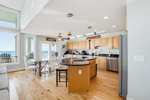Eine moderne Küche mit Holzschränken, einem Edelstahlkühlschrank und einer großen Kücheninsel mit Spüle.