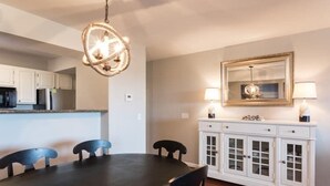 A dining area with a dark table, chairs, a chandelier, a white cabinet with glass doors, and a mirror on the wall. - 189 Beach Club Villa (Fripp Island)